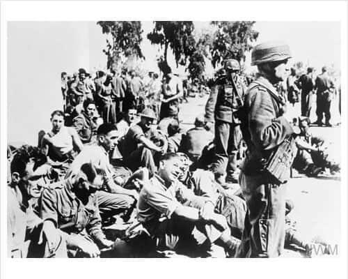 British prisoners of war under the guard of German paratroopers after being captured in Greece, 10-20 May 1941. © IWM HU 39535
