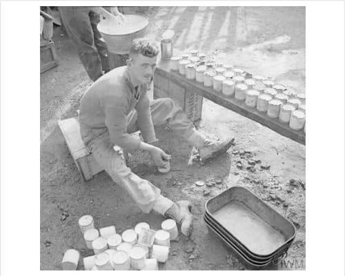 A soldier opening tins at a field kitchen, 13 November 1943.© IWM (NA 9082)